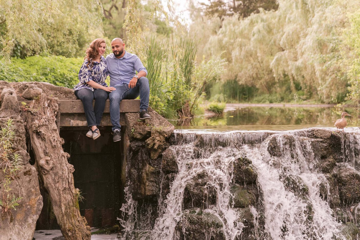 A couple sit next to a waterfall at Edwards Gardens in Toronto