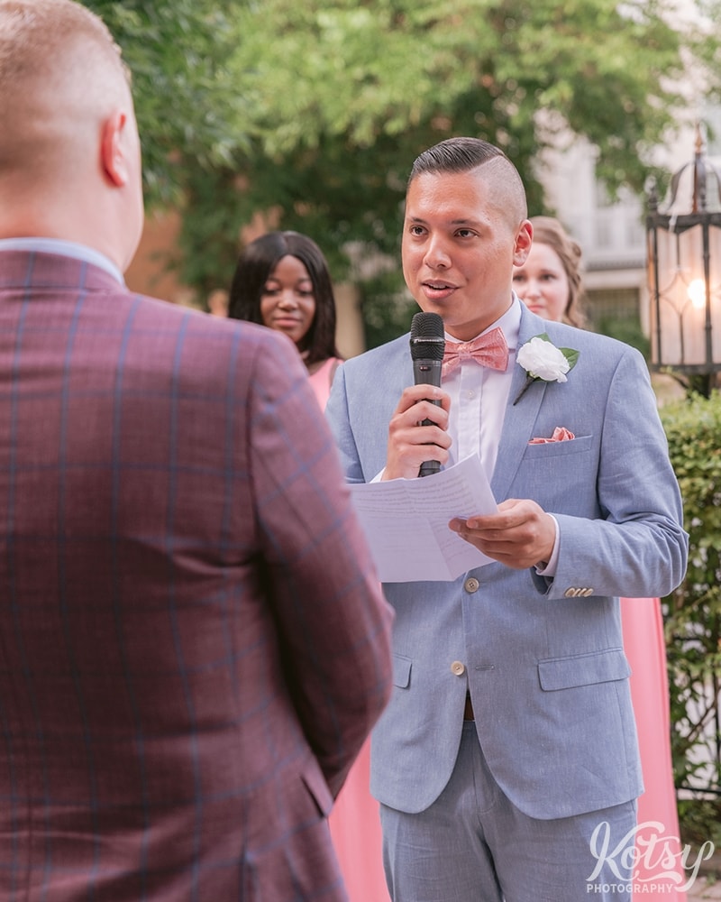 A groom reads his partner his vows at their outdoor wedding ceremony at Berkeley Bicycle Club in Toronto, Ontario