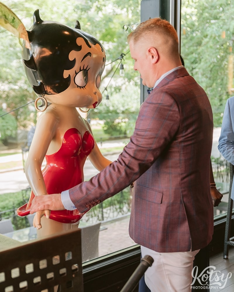 A groom holds hands with a Betty Boop life-size statue at Berkeley Bicycle Club in Toronto