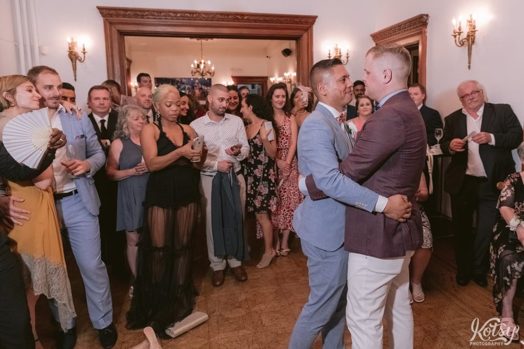 Two grooms enjoy their first dance during their wedding ceremony at Berkeley Bicycle Club in Toronto