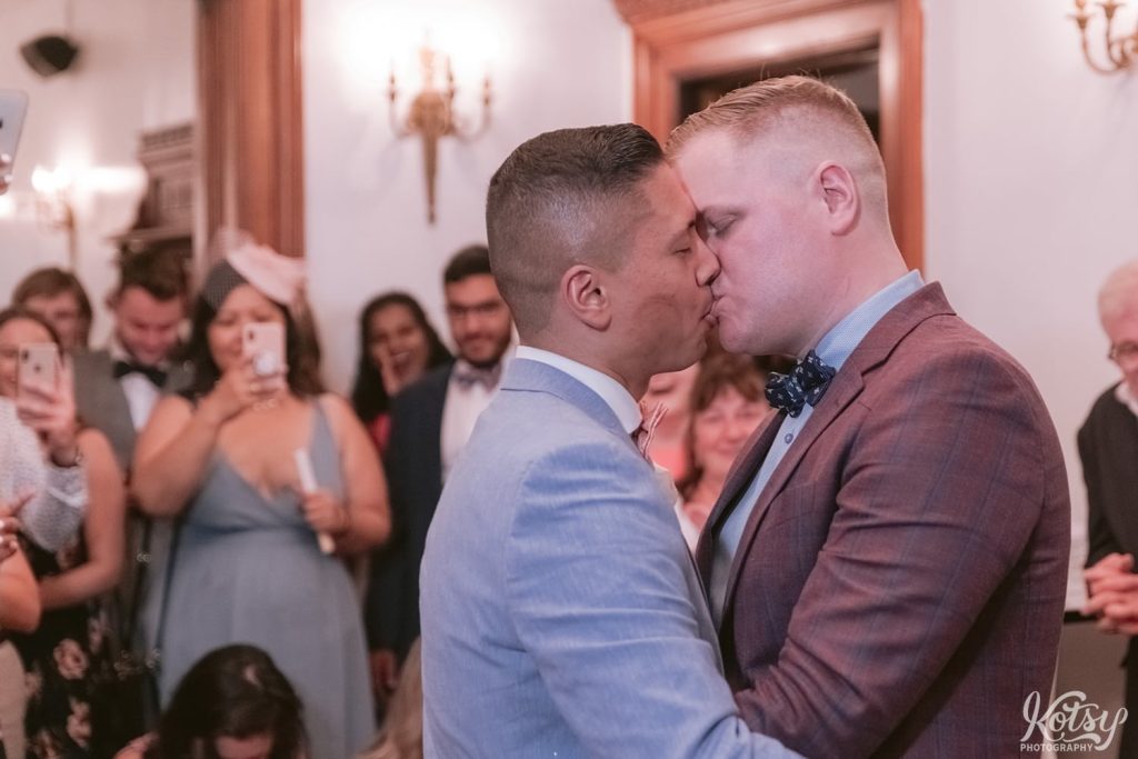 Two grooms kiss during their first dance at their wedding reception. Photographed at Berkeley Bicycle Club in Toronto