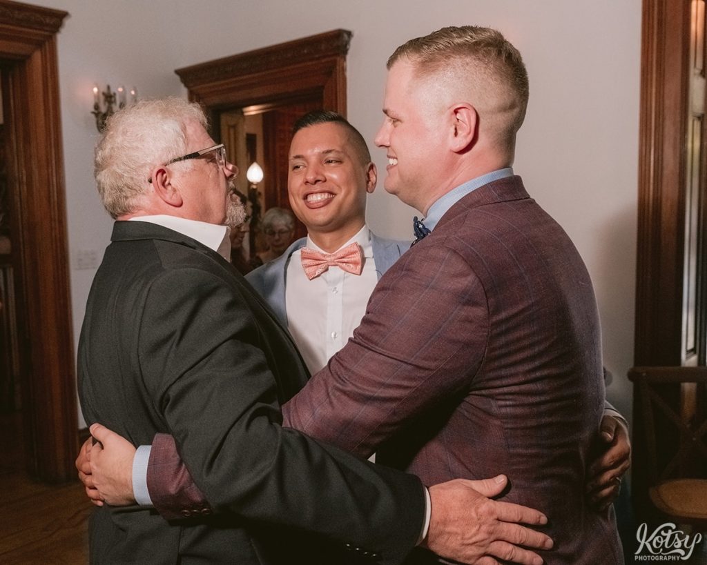 Two grooms dance with a father during their wedding reception at Berkeley Bicycle Club in Toronto.