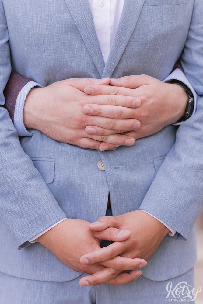 A close up shot of a groom's hands holding his partner's stomach at Berkeley Bicycle Club in Toronto