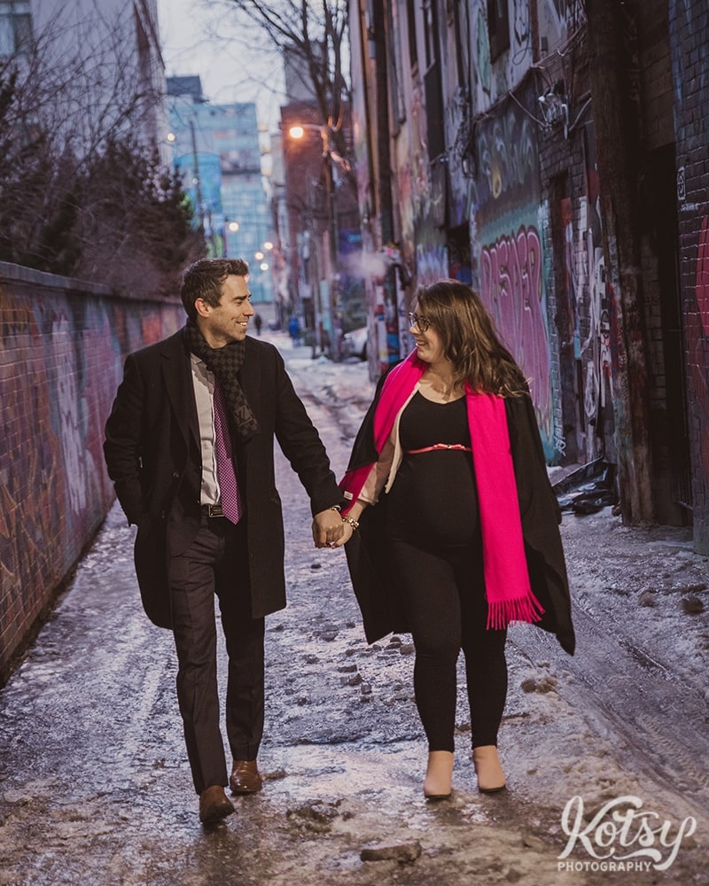 A couple walk hand-in-hand through Graffiti Alley in a winter day in Toronto