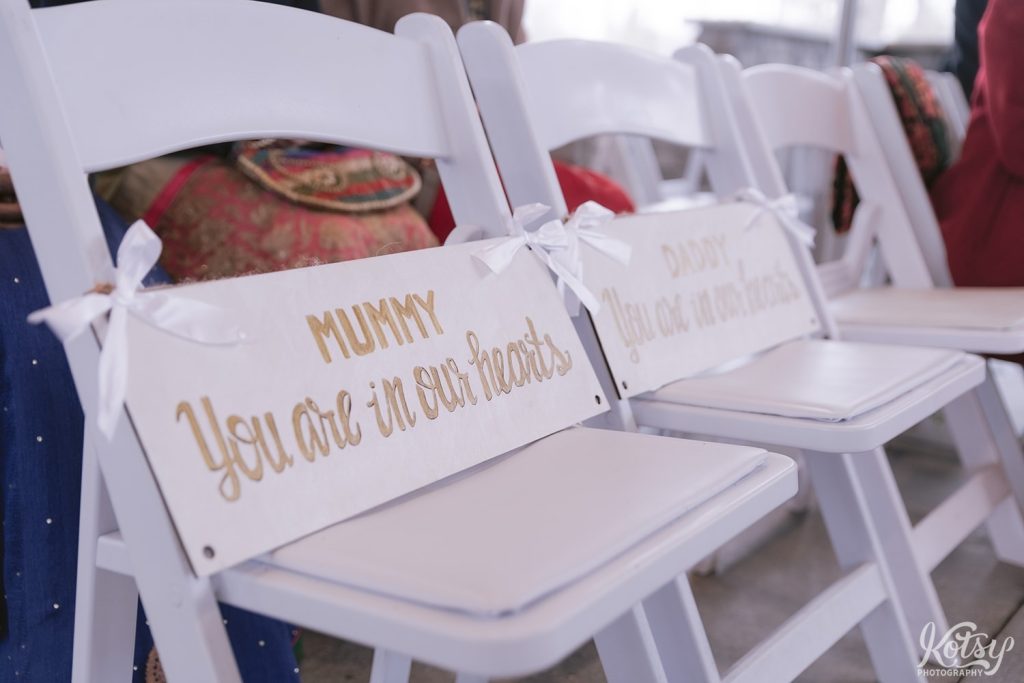 A shot of two wooden placards in memory of a groom's parents that weren't able to make a wedding ceremony.