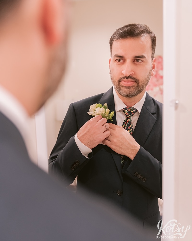 A groom adjusts his corsage before his wedding reception at Guild Inn Estate