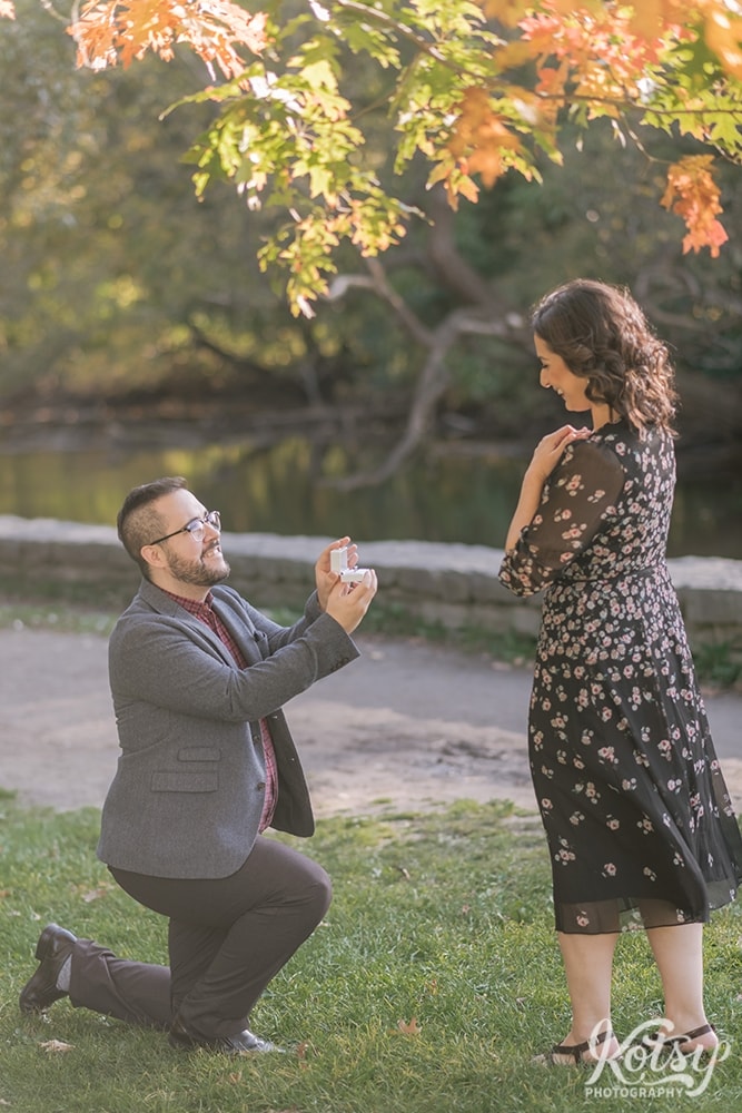 A man proposes to his girlfriend to much surprise by a waterfront at High Park in Toronto