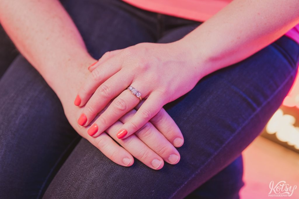 A shot of an engagement ring on a newly engaged woman. Photographed at Neon Demon Studio in Toronto, Ontario
