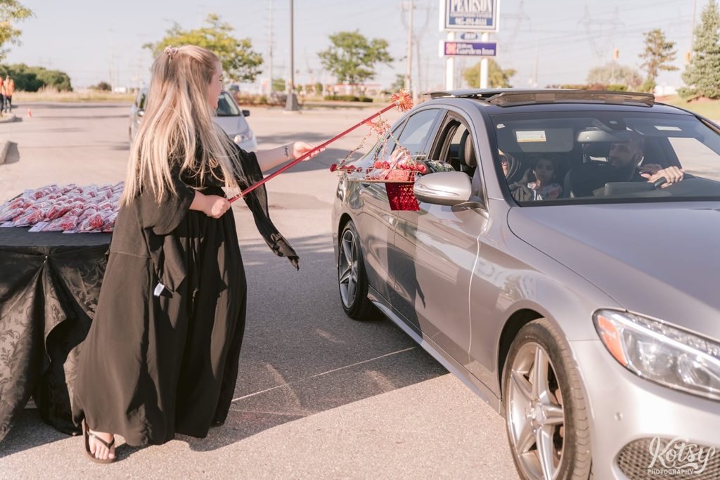 A woman passes a car gifts as they arrive at a drive-thru wedding at the Pearson Convention Centre in Mississauga, Ontario