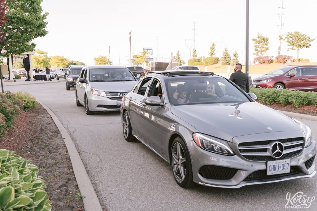 A long line of cars for their time to greet and get a photo with the bride and groom at a drive through wedding. Photographed at the Pearson Convention Centre in Mississauga, Ontario