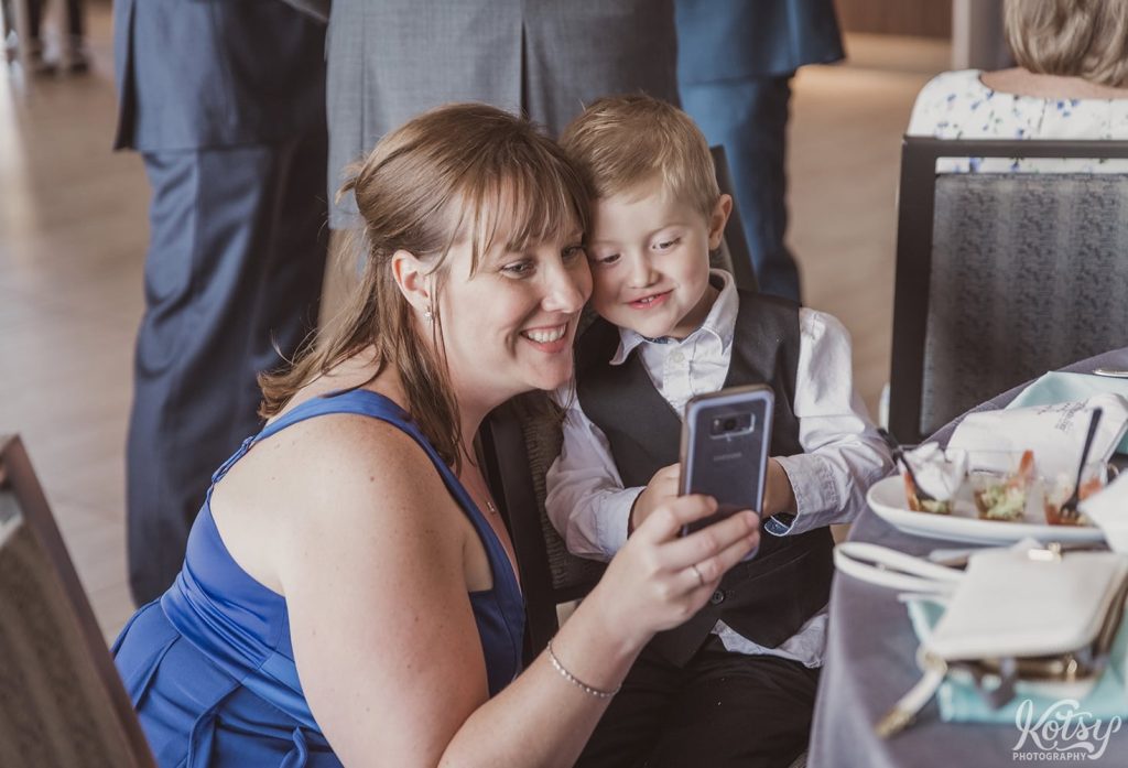 A woman and a little boy watch a video on her cell phone at a wedding reception at Universal EventSpace in Vaughan