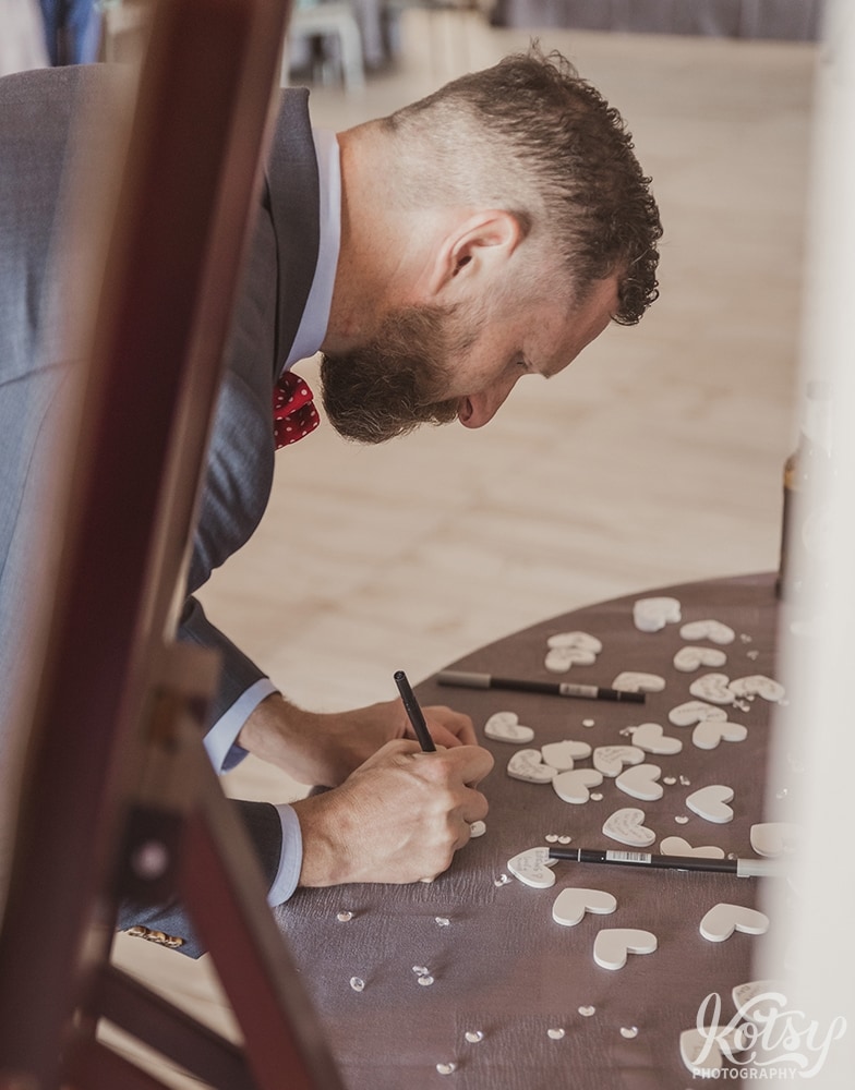 A man writes on a wooden heart at a wedding reception at Universal EventSpace in Vaughan