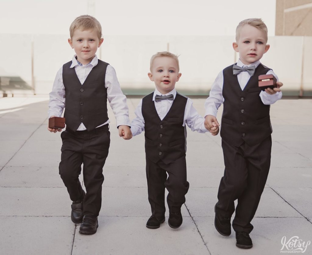 2 ring bear's and another little boy make their way down an aisle for a wedding ceremony on an outdoor patio at Universal EventSpace