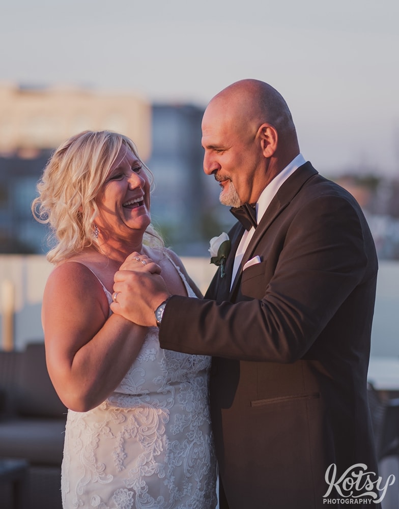A bride lets out a huge laugh while dancing with her groom on a patio at Universal EventSpace