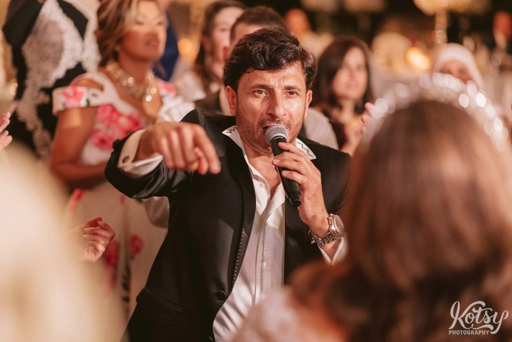 A man sings into a microphone at a wedding reception.