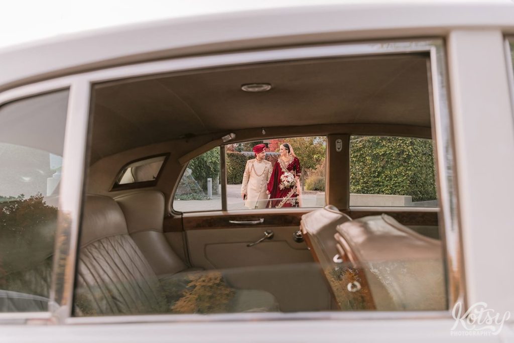A bride and groom are seen through the rear windows of a Rolls Royce