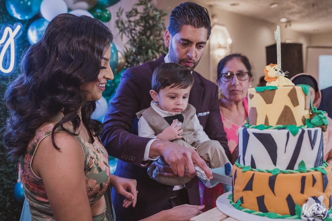 A husband and wife cut a cake with their son at his birthday party.