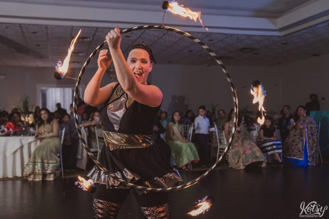 A performer spins a hoola hoop with bits of fire.
