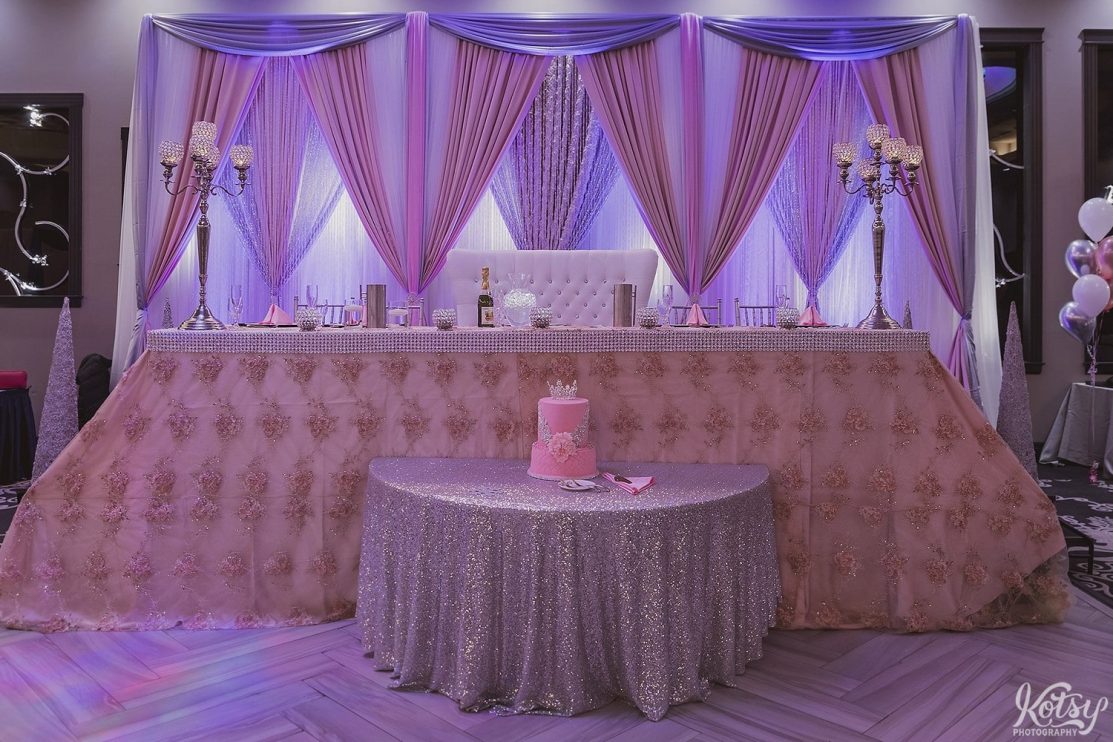 Shot of a fancy head table setup with two two tier cake at a sweet 16 birthday party.