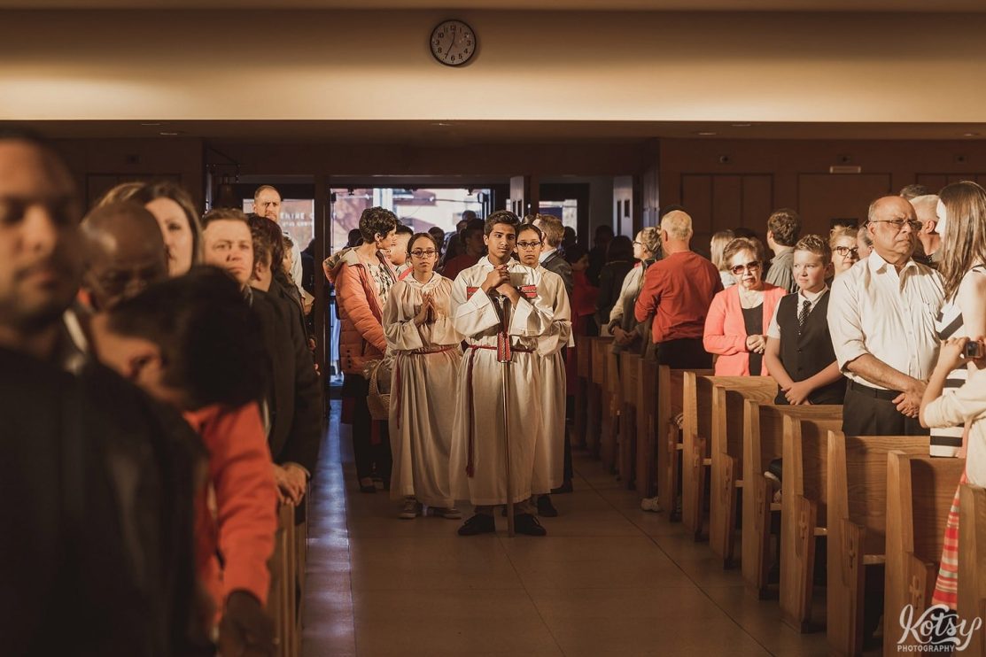 Young men and women make their way down the aisle of a church during a confirmation ceremony.