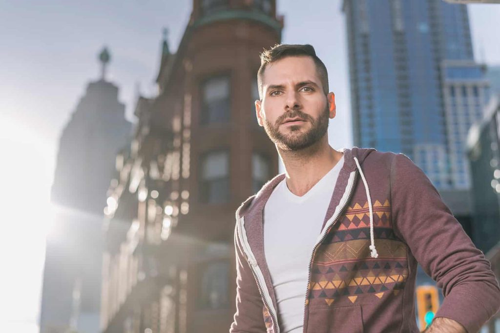 A male poses for a portrait in front of the flatiron building in Toronto