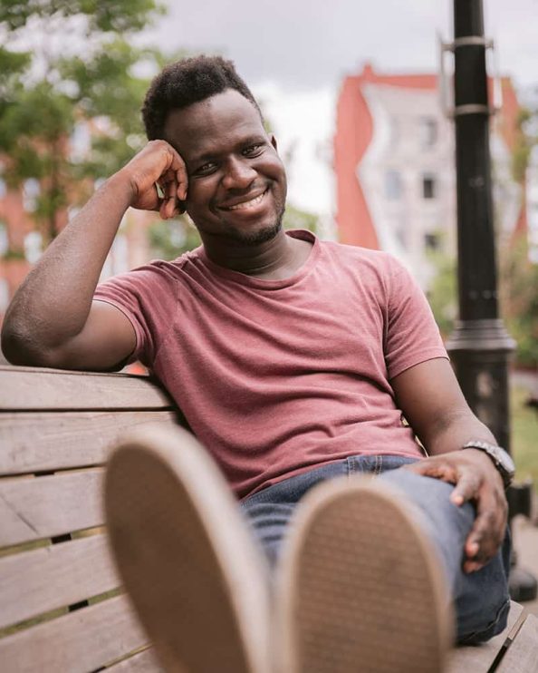 A man poses for a portrait while sitting on a bench at Berczy Park in Toronto