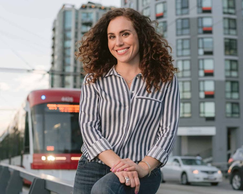 A woman poses for a portrait in front of a passing streetcar in Toronto