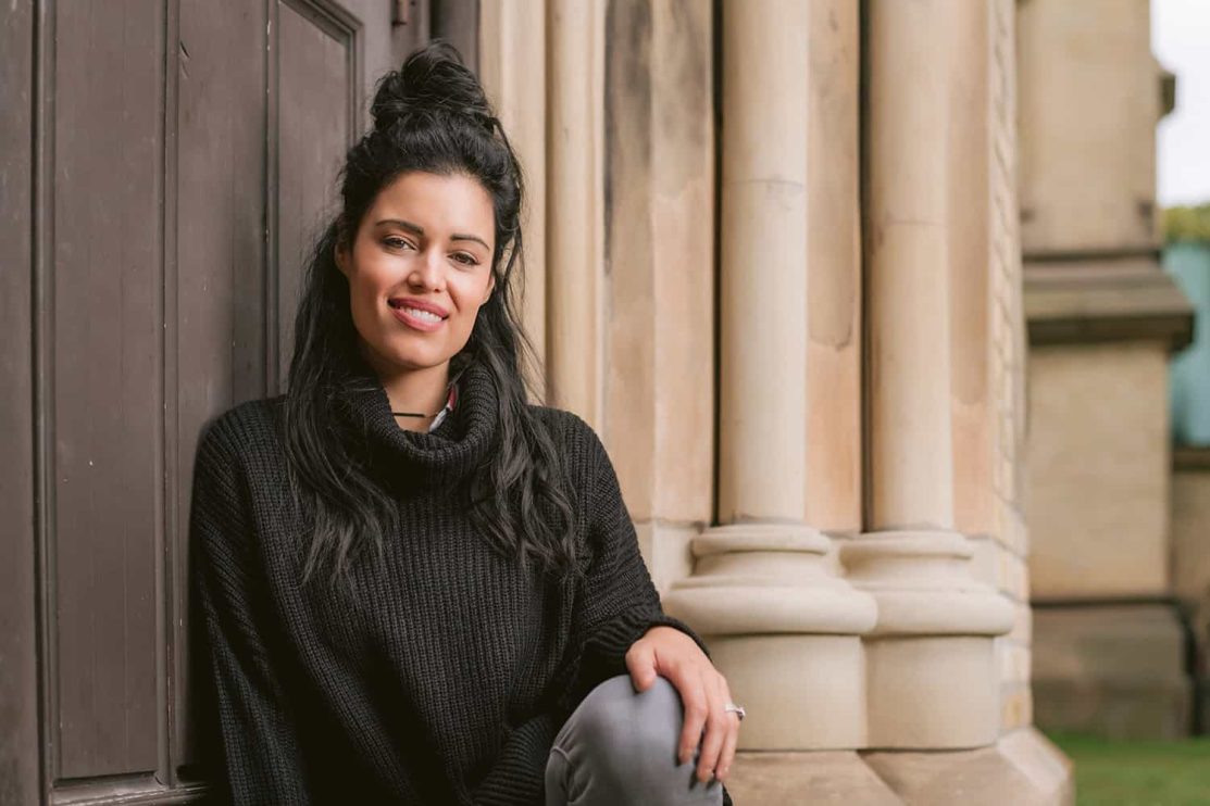 A woman poses while sitting on the steps in front of a church in Toronto