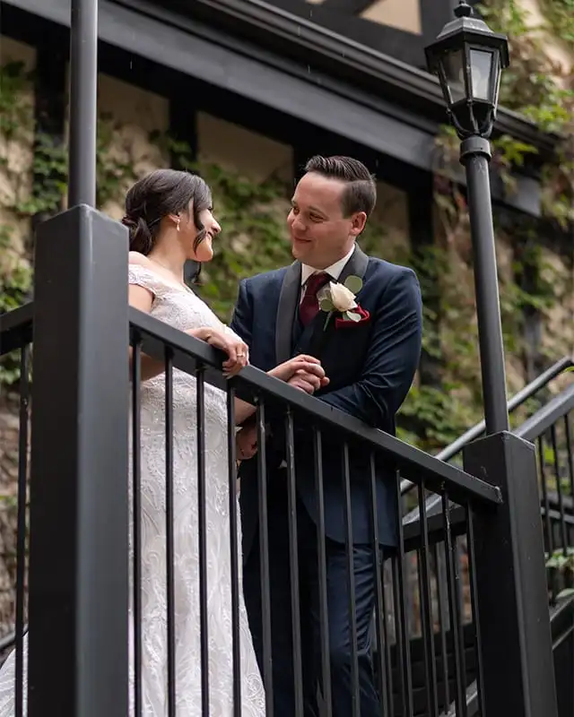 A bride and groom exchange smiles while standing on a black steel staircase