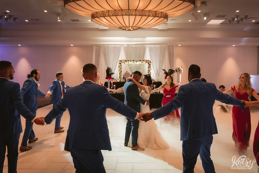 A bride and groom dance as their bridal party dances around them in a circle