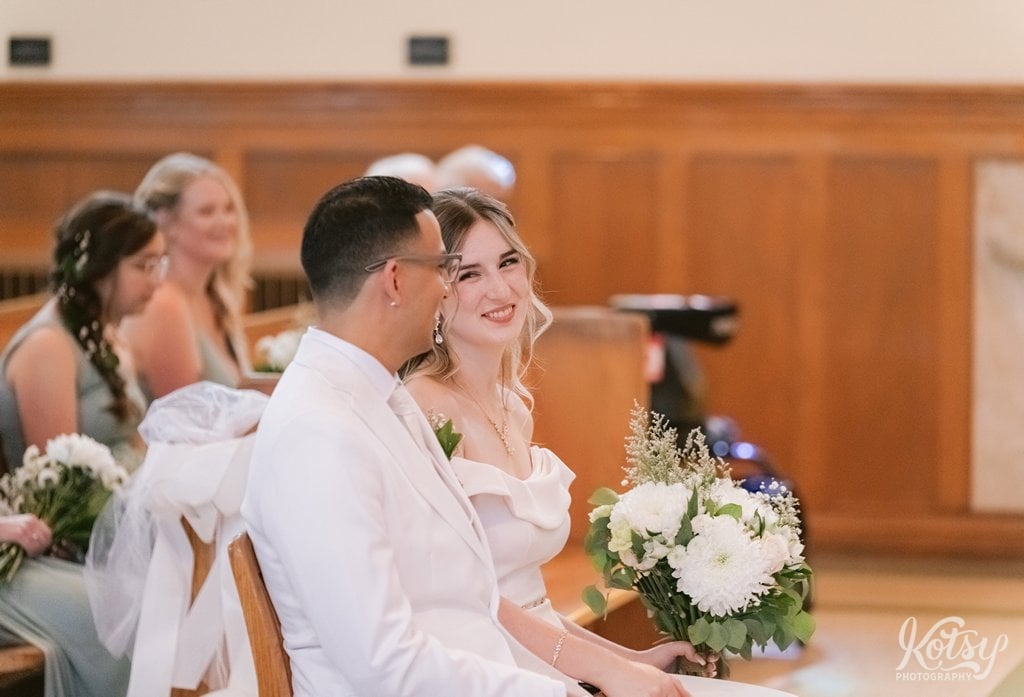 A bride gives her groom a lovingly look while sitting at the alter during their wedding ceremony
