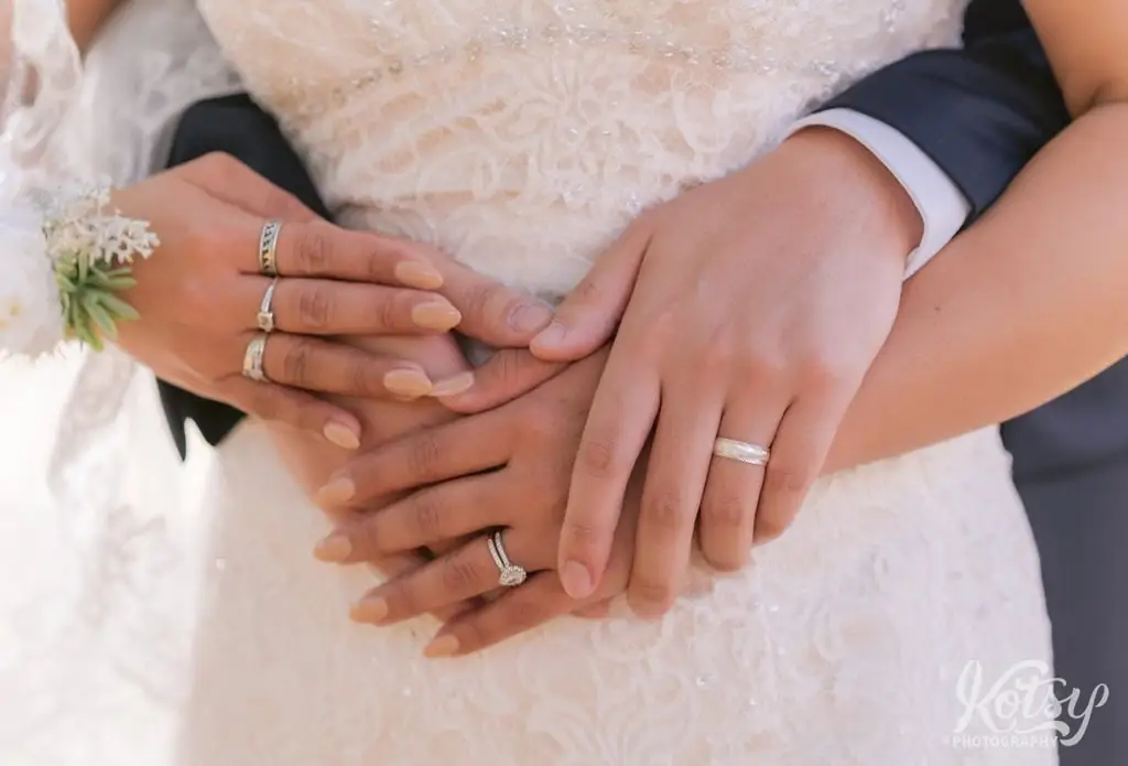 A close up shot of a groom and bride's hands upon a bridal gown.