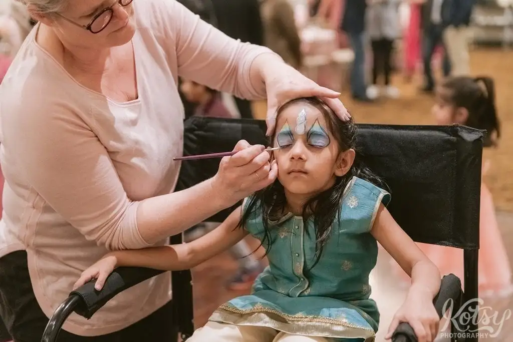 A young child gets her face painted