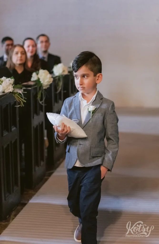 The ring bearer makes his way down the aisle at the Old Mill chapel in Toronto