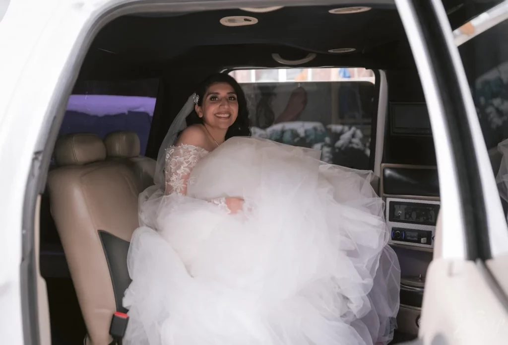 A bride smiles for the camera while sitting in her limo before departing to Old Mill in Toronto for her wedding ceremony