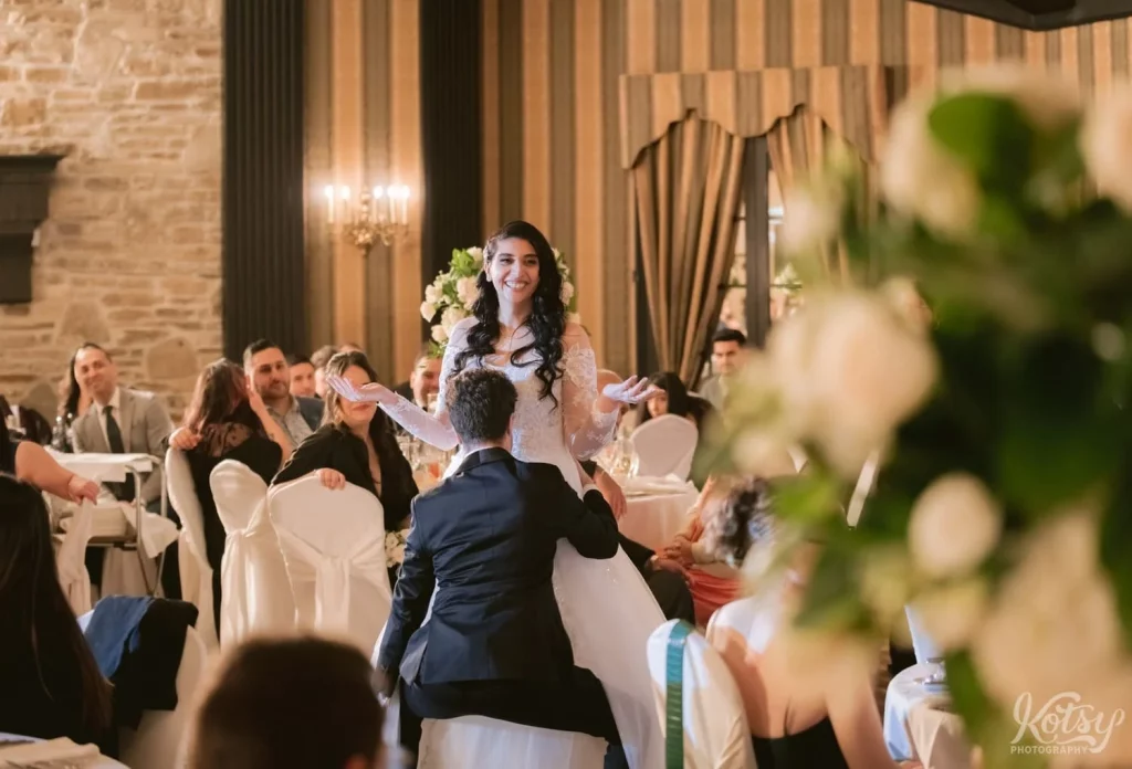 A groom does a jiggly dance in front of his bride at their Old Mill wedding reception