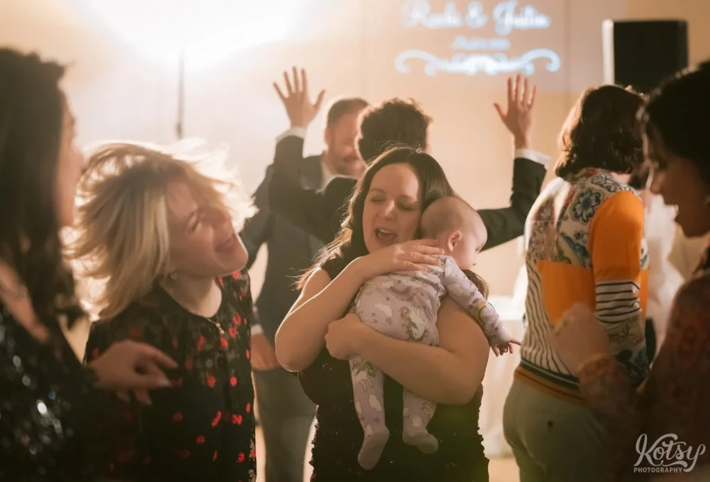 A woman dances with her baby at an Old Mill wedding reception in Toronto