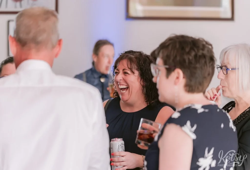 A woman enjoys a laugh with a group of people at a wedding in Toronto, Canada