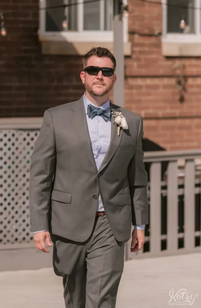A groom sporting sunglasses struts down the aisle at his outdoor wedding ceremony in Toronto