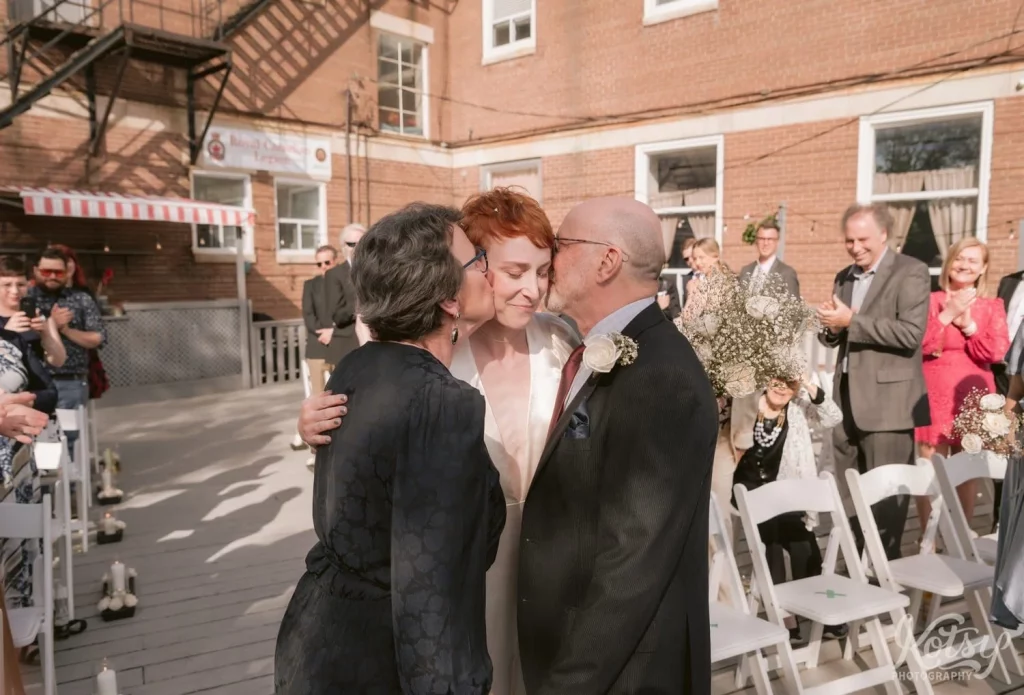 A bride is kissing by her parents upon her arrival to the alter at her outdoor wedding at Royal Canadian Legion 344 in Toronto
