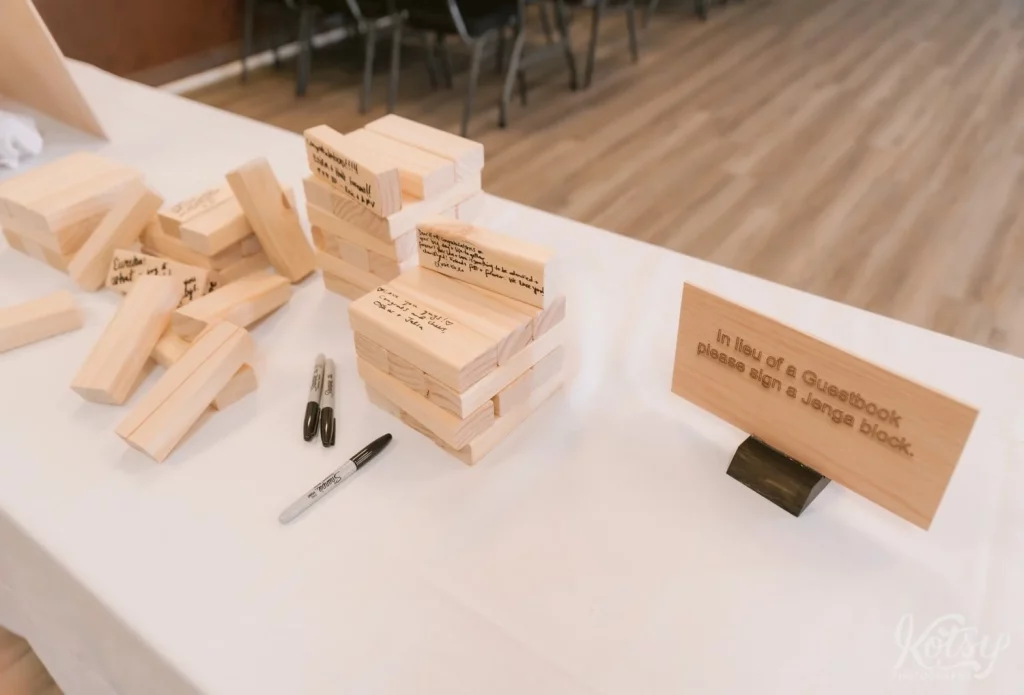 A laser engraved wood sign instructing wedding guests to sign a jenga block in lieu of a guestbook