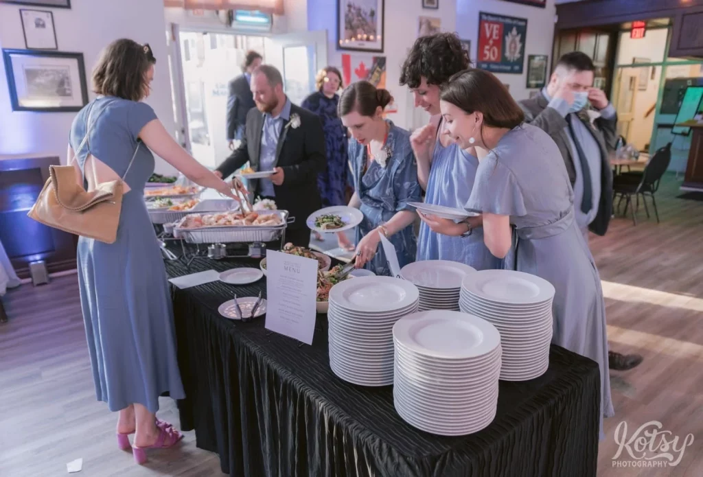 Bridesmaids help themselves to food at a buffet during a wedding in Toronto