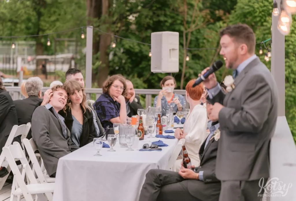 A couple is seen cuddling during a speech at an outdoor wedding reception in Toronto