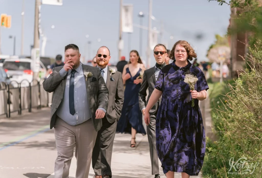 A man inhales from a cigarette as he walks with a group of wedding guests down a path in Toronto, Canada
