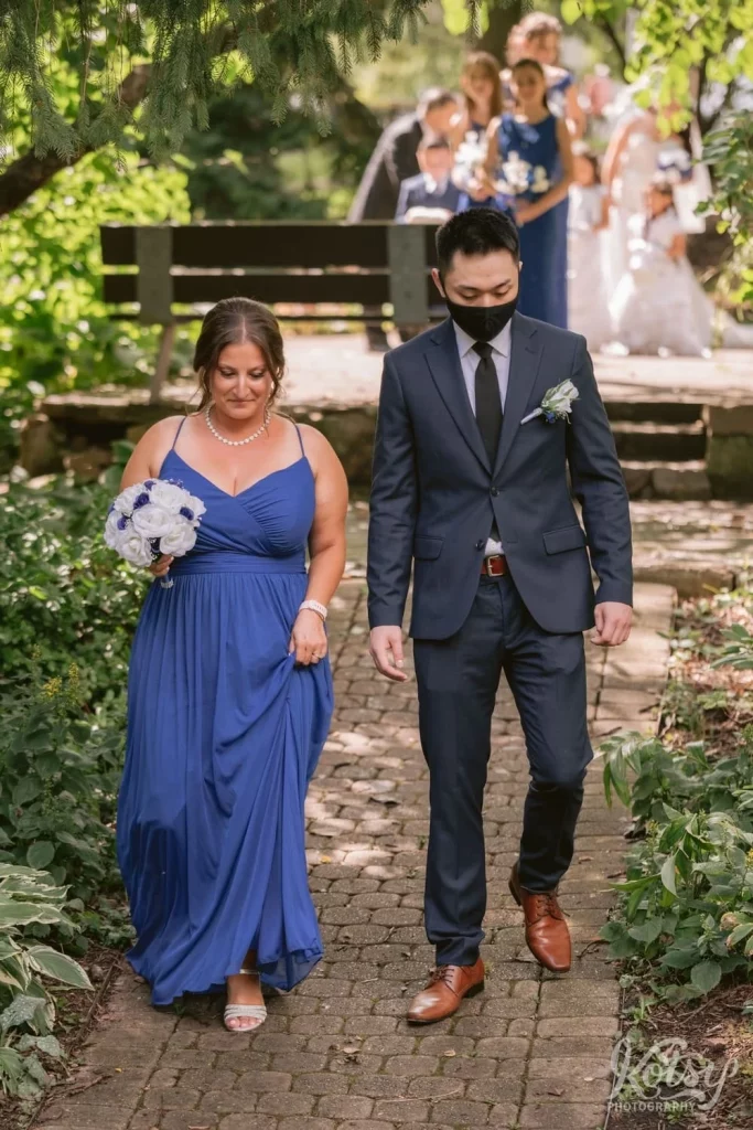 A maid of honour and best man make their way down the aisle at an outdoor wedding at Rosetta McClain Gardens in Toronto
