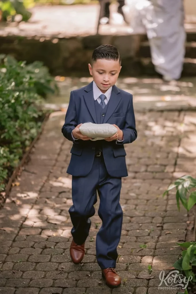 A ring bearer makes his way down the aisle during at wedding ceremony at Rosetta McClain Gardens