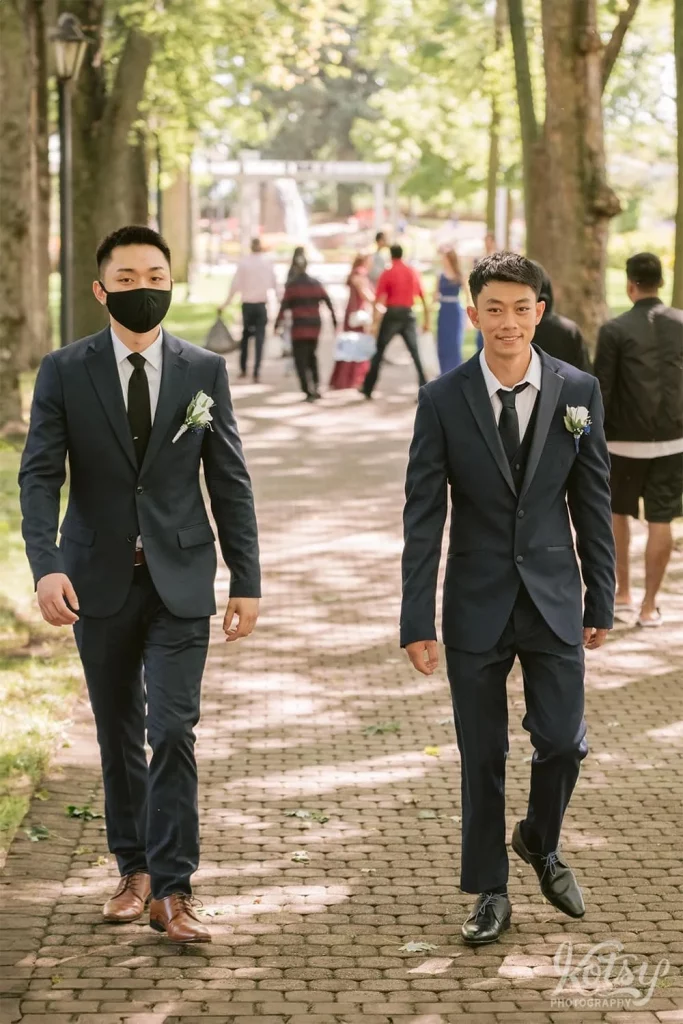 A groom and his best man walk down a path at Rosetta McClain Gardens in Toronto