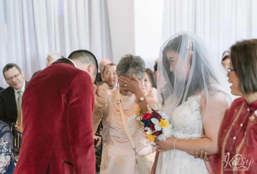 A grandmother covers her eyes as she tears up during her grand daughters wedding ceremony in Toronto