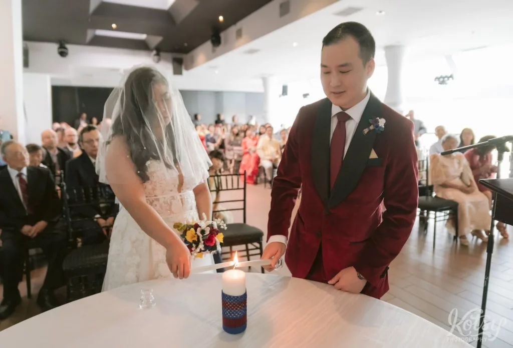A bride and groom light a candle during their wedding at The Vue Event Venue in Toronto