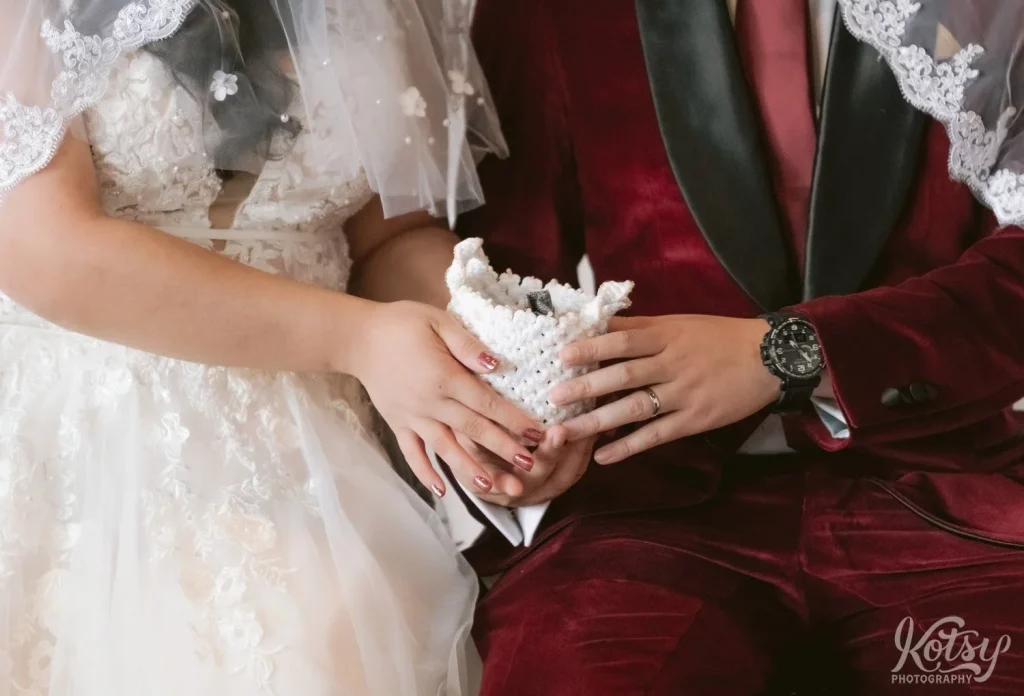 A bride and groom hold a basket with 13 coins, as per Filipino tradition, during their wedding ceremony